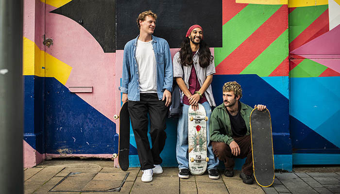 Three skateboarders standing against a wall decorated with Street Art in Limerick